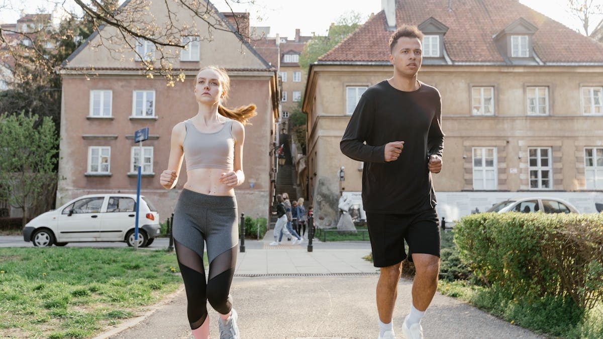 Two young adults jogging on a city path, showcasing an active lifestyle in an urban environment.